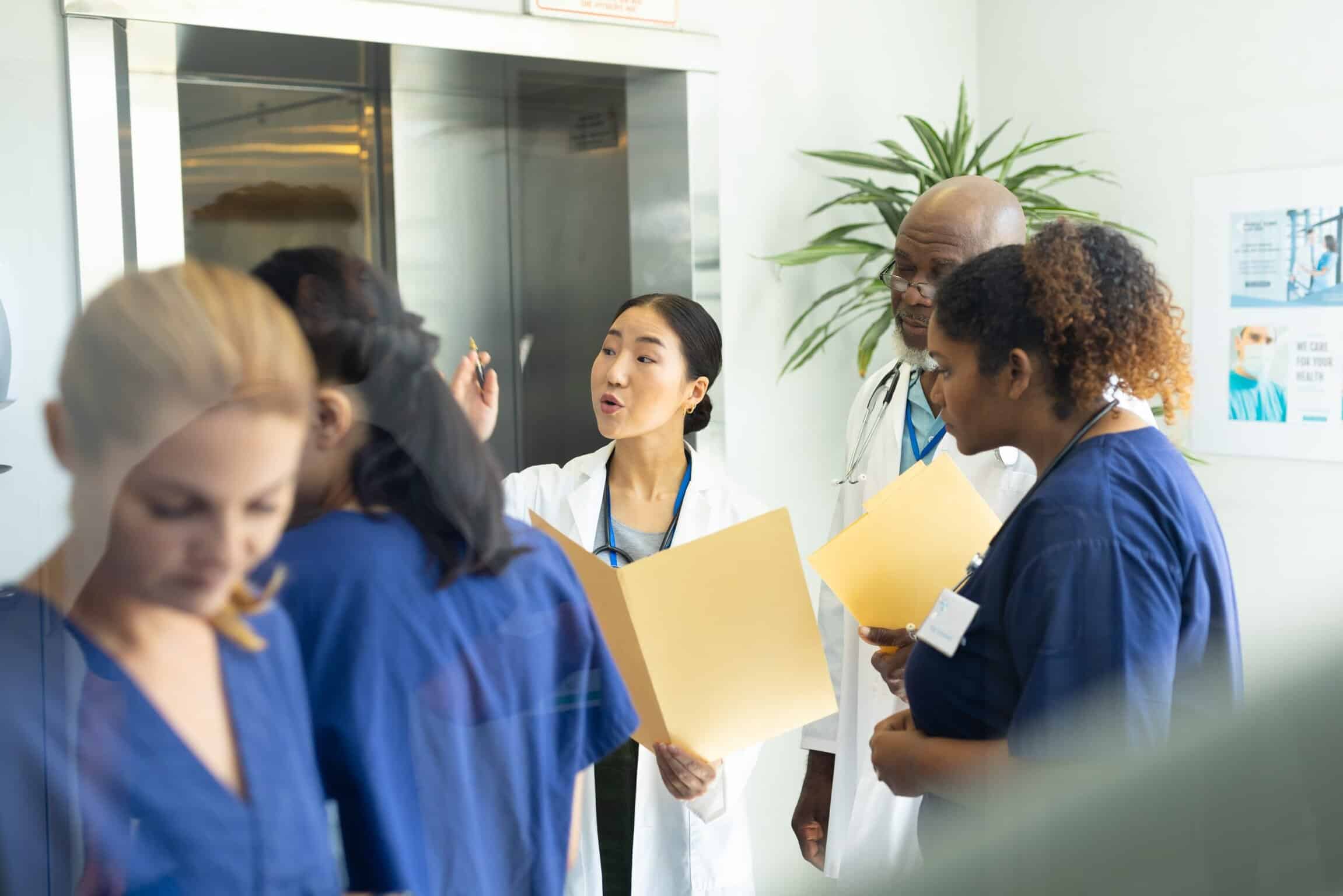 Why Hybrid Medical Pathways Are Key to UK & US Residency Success diverse group male female doctors holding files discussing busy hospital corridor hospital medical healthcare services scaled
