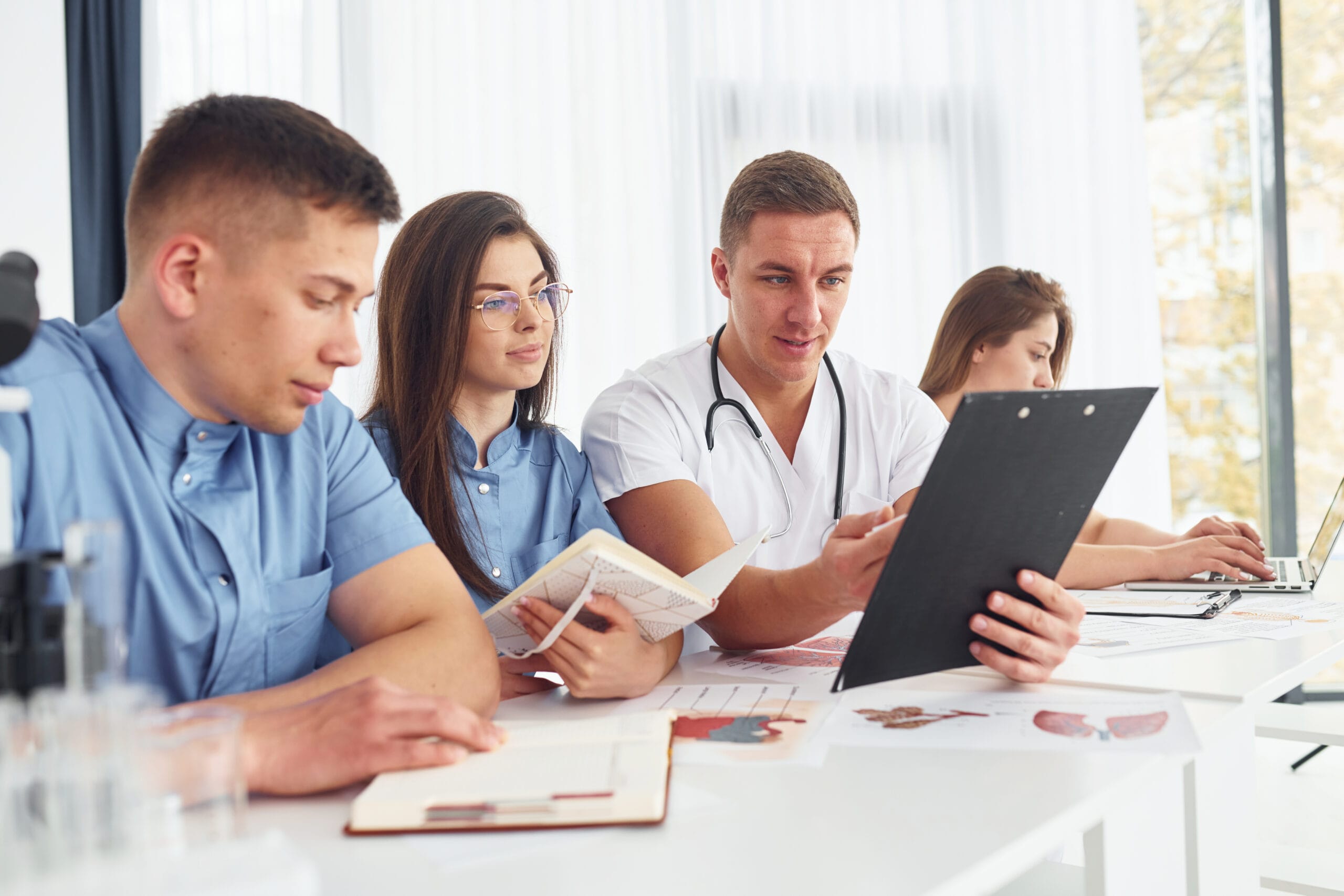 sitting by table group young doctors is working together modern office scaled